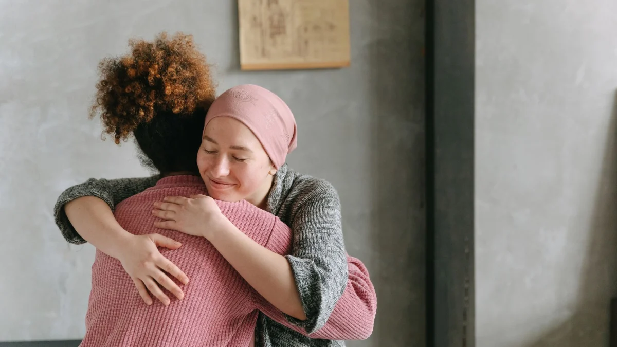 Twee vrouwen omhelzen elkaar met warmte en liefde, wat steun en zorg binnen symboliseert.