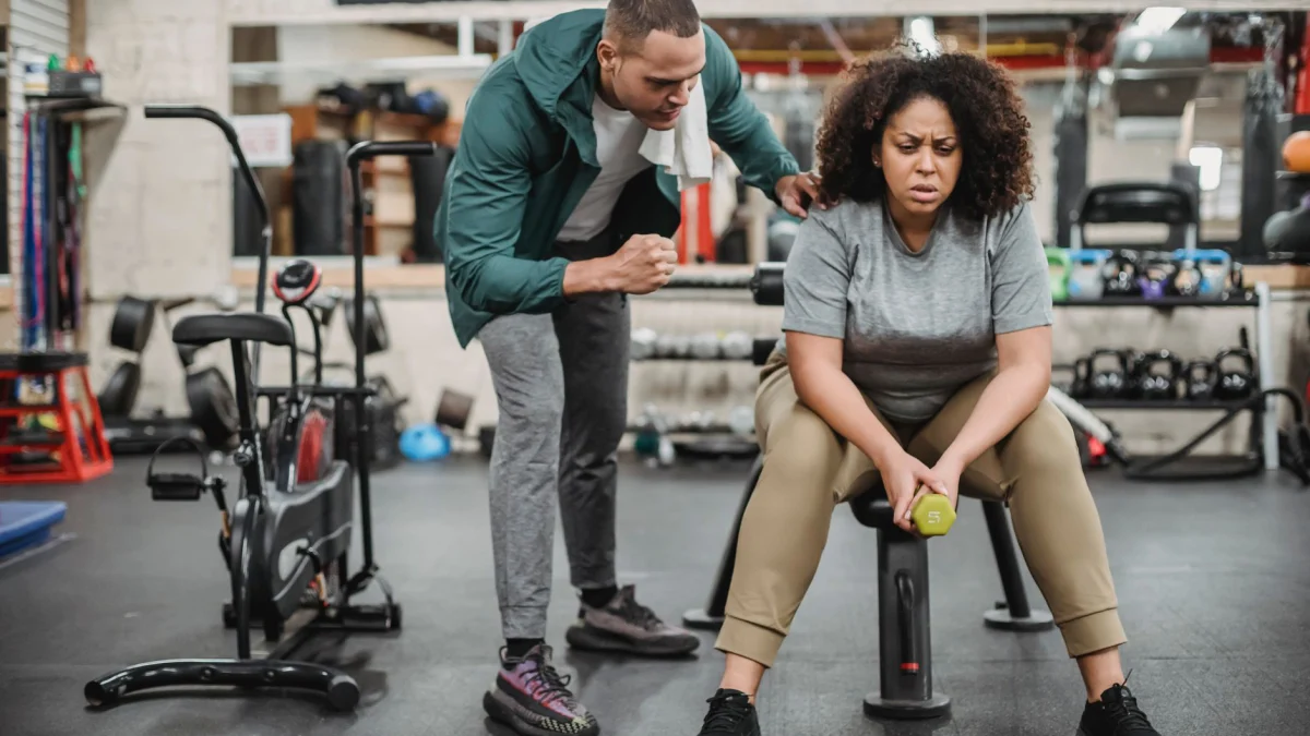 Een persoonlijke trainer motiveert een vrouw tijdens haar fitness trainingssessie in een sportschool.