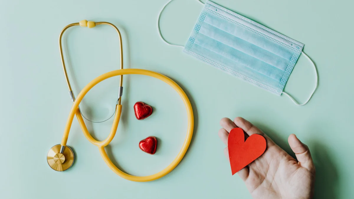 Flat lay van medische hulpmiddelen met een stethoscoop, masker en hartvormen die essentiële gezondheidszorg vertegenwoordigen.
