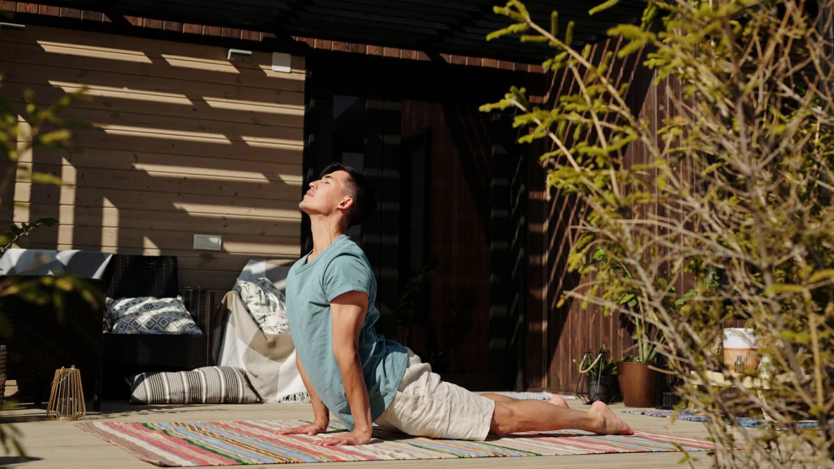Man die yoga doet in zonlicht, gezond en ontspannen op een veranda.