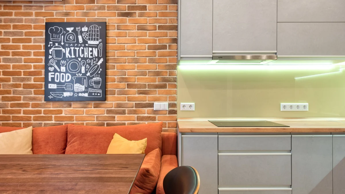 Elegante keukenruimte met moderne kasten en baksteendecor, die een gezellig ontwerp laat zien.