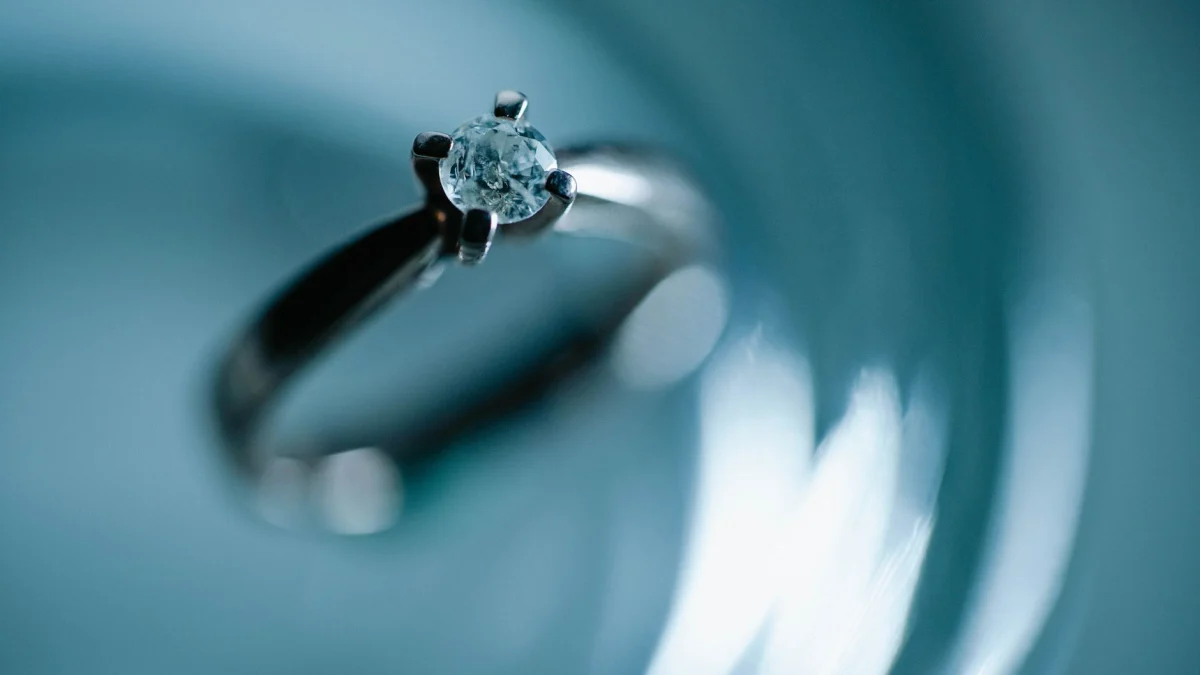 Close-up van een diamanten verlovingsring op een glinsterend blauwe ondergrond, die elegantie en romantiek oproept.