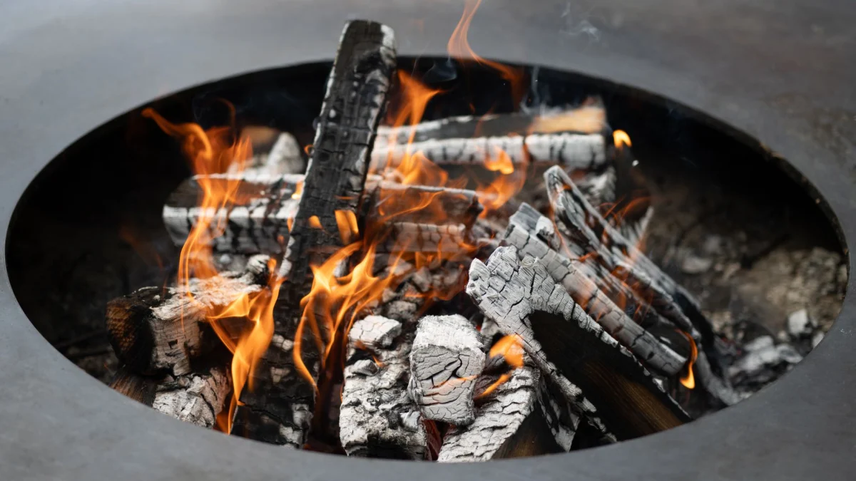 Een close-up van brandend hout met felle vlammen in een metalen vuurkorf.