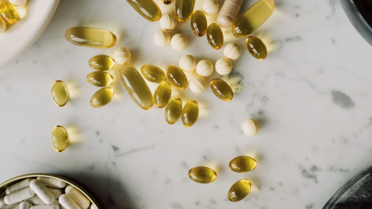 Bovenaanzicht van verschillende capsules en pillen verspreid over een marmeren oppervlak, ideaal voor medische of farmaceutische thema's.
