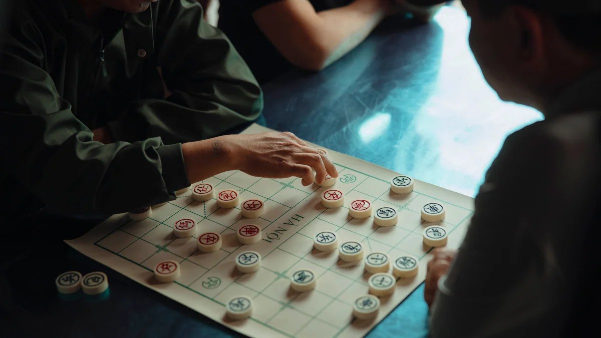 Twee mannen zijn bezig met een strategisch Chinees schaken, wat een intense binnenlandse sfeer creëert.