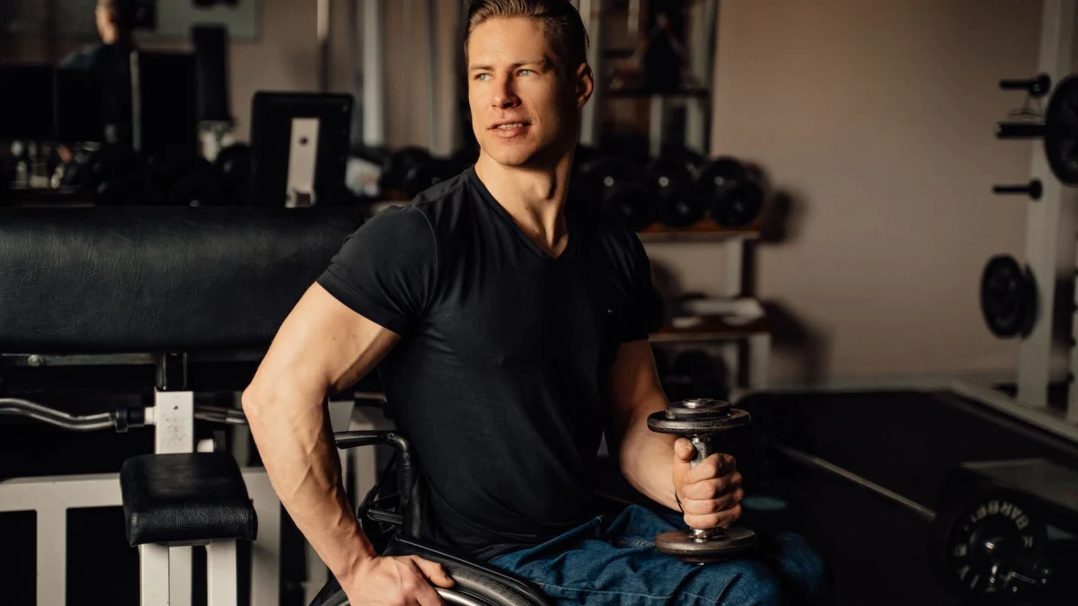 Een gespierde man in een rolstoel die binnen een dumbbell til, toont vastberadenheid en fitheid.