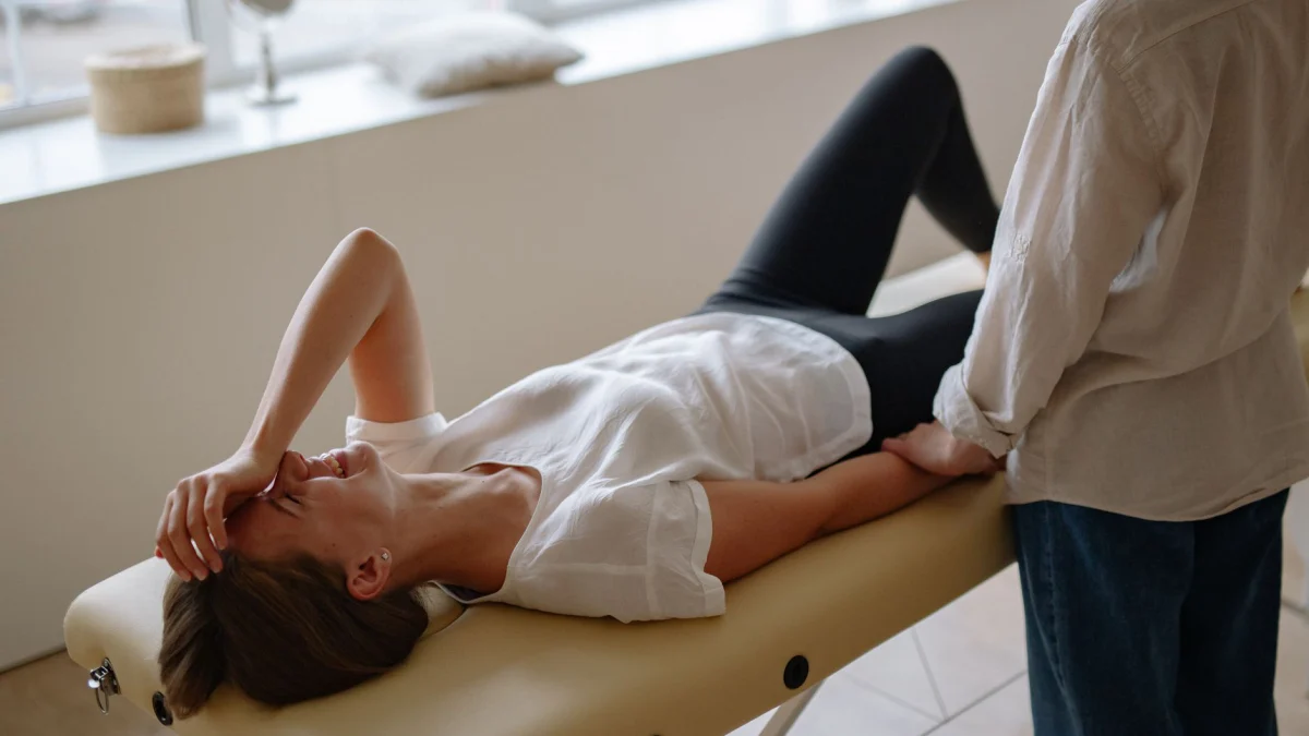 Vrouw in witte top geniet van een ontspannende massagesessie binnen, glimlachend en comfortabel liggend.
