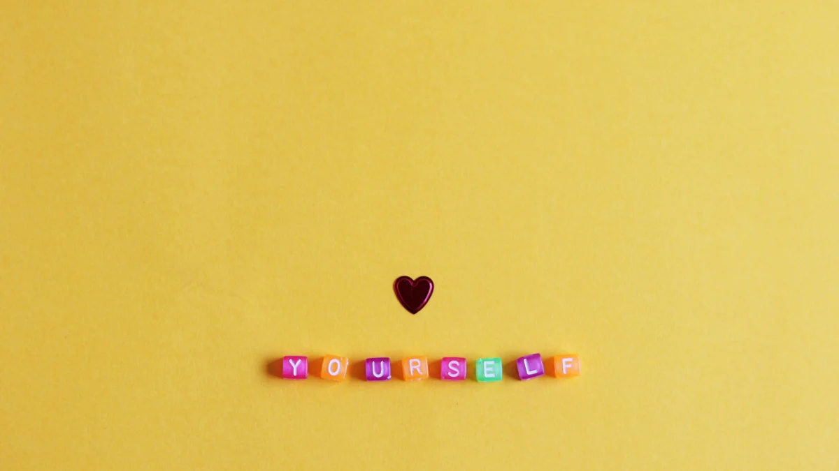 Felle minimalistische opstelling met een hart en 'YOURSELF' op een gele achtergrond.