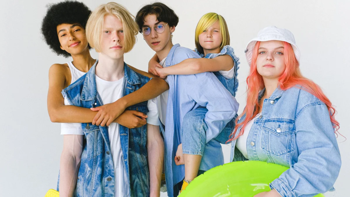 Portret van een diverse groep tieners, casual gekleed in denim, die binnenshuis plezier hebben.