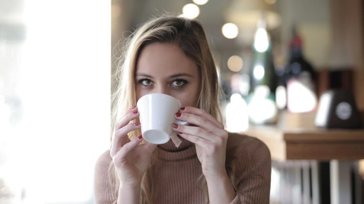 Een jonge vrouw in een gezellige trui die een warm drankje drinkt in een ontspannen interieur.