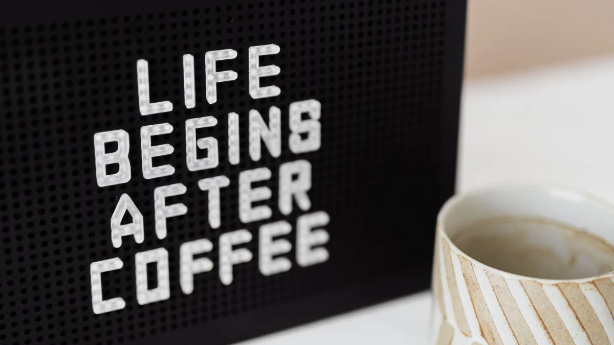 Stijlvolle mok naast een bord met een motiverende koffiebericht voor 's ochtends.