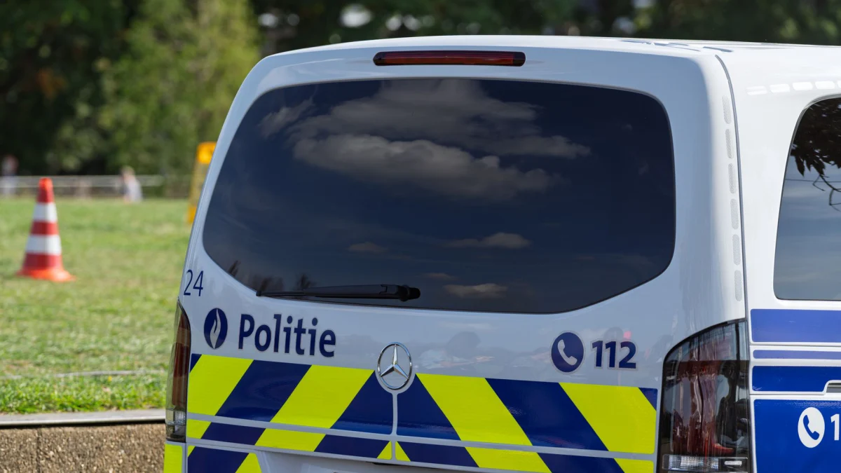 Close-up van een Belgische politiebus die op een zonnige dag buiten geparkeerd staat, met zichtbare politie-aanduidingen.