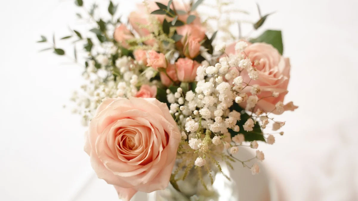 Een delicate schikking van roze rozen en gipskruid die een romantische bloemenaankleding creëert.