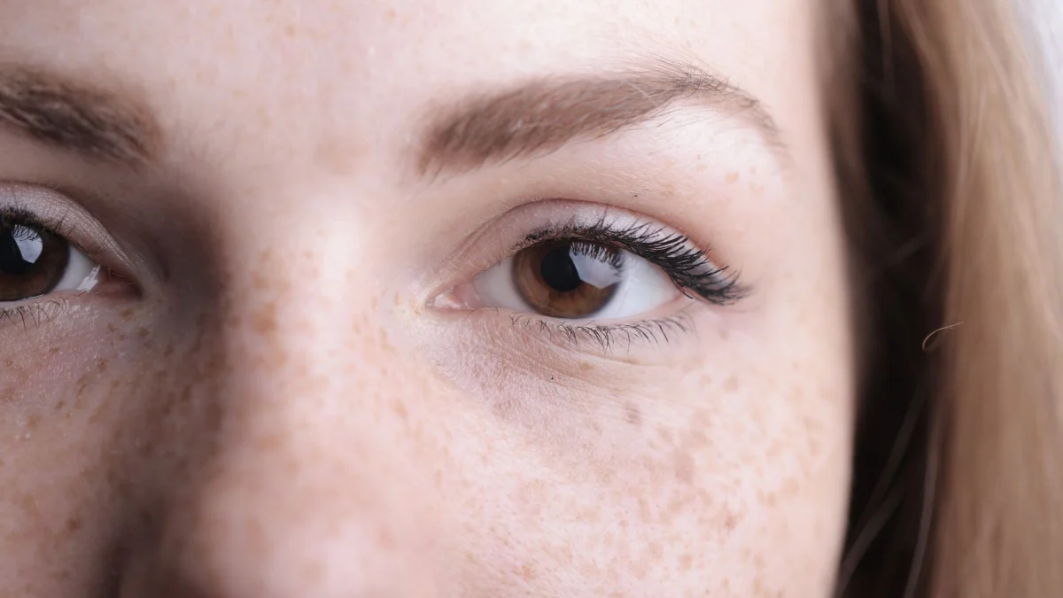 Een gedetailleerde close-up van de ogen van een vrouw en sproeten die natuurlijke schoonheid benadrukken.