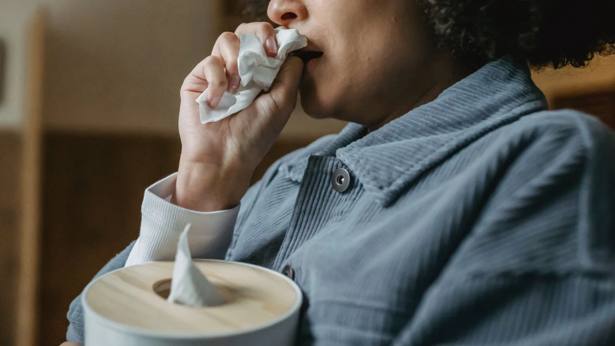 Close-up van een vrouw met tissues die verdriet binnenshuis uitdrukt.