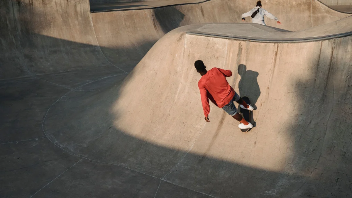 Twee skateboarders voeren tricks uit in een buiten stads skaterpark tijdens zonsondergang.