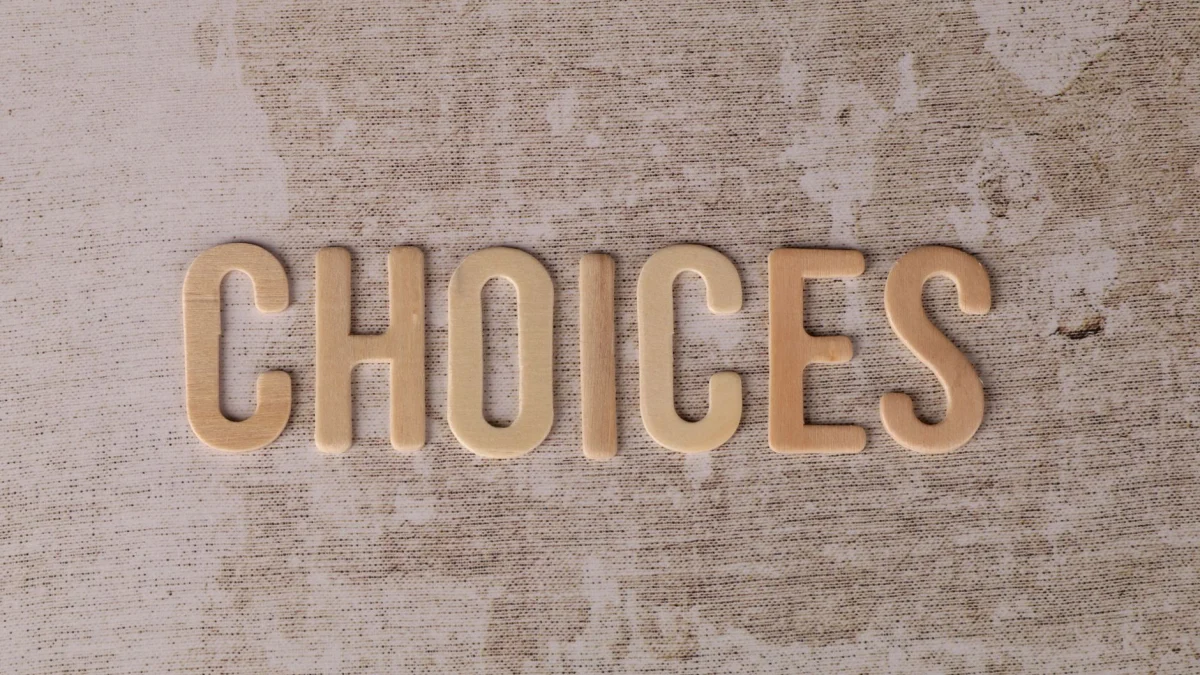 Houten letters die 'keuzes' spellen op een textuuroppervlak, symbool voor besluitvorming.