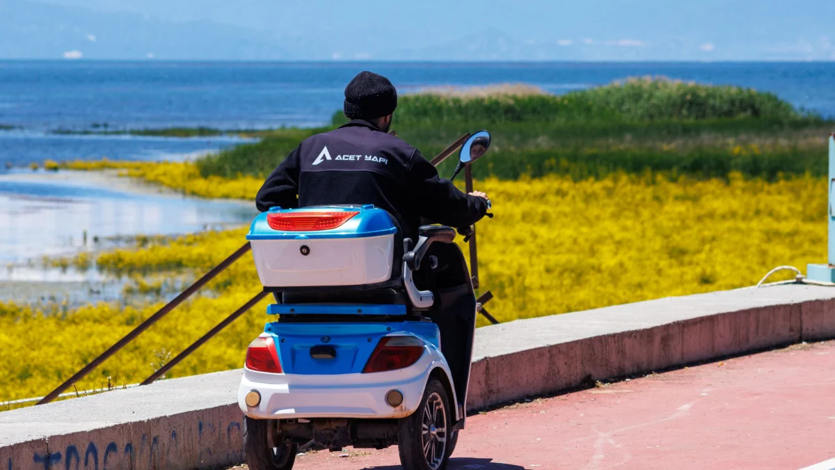 Een persoon rijdt op een scootmobiel over het levendige pad langs het Beyşehir-meer in Turkije.