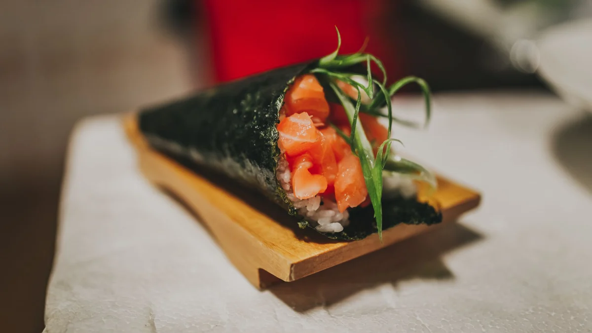 Heerlijke temaki sushi-cone met zalm en zeewier op een houten bord, die de Japanse keuken benadrukt.
