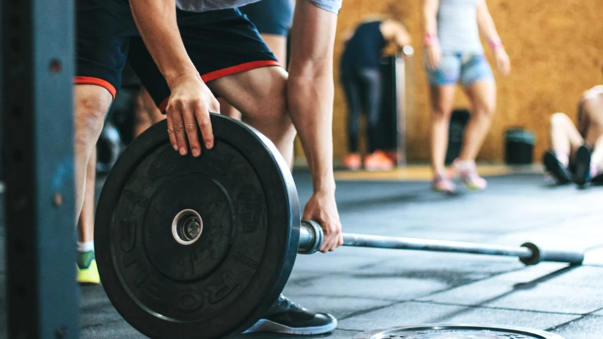 Geconcentreerde gewichthefsessie in een sportschool met diverse atleten die binnenshuis deelnemen.