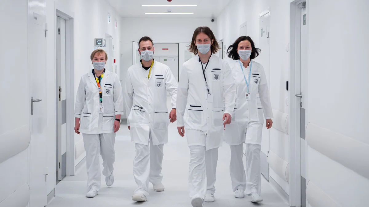 Medisch team loopt zelfverzekerd in een ziekenhuisgang, draagt mondmaskers en witte jassen, symboliseert teamwork en toewijding aan de gezondheidszorg.