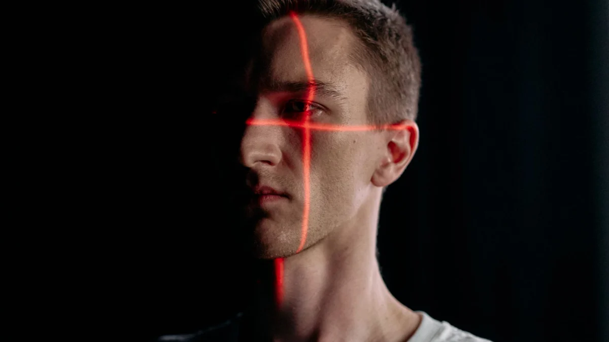 Studioportret van een man met een laserroosterpatroon voor gezichtsherkenning op een zwarte achtergrond.