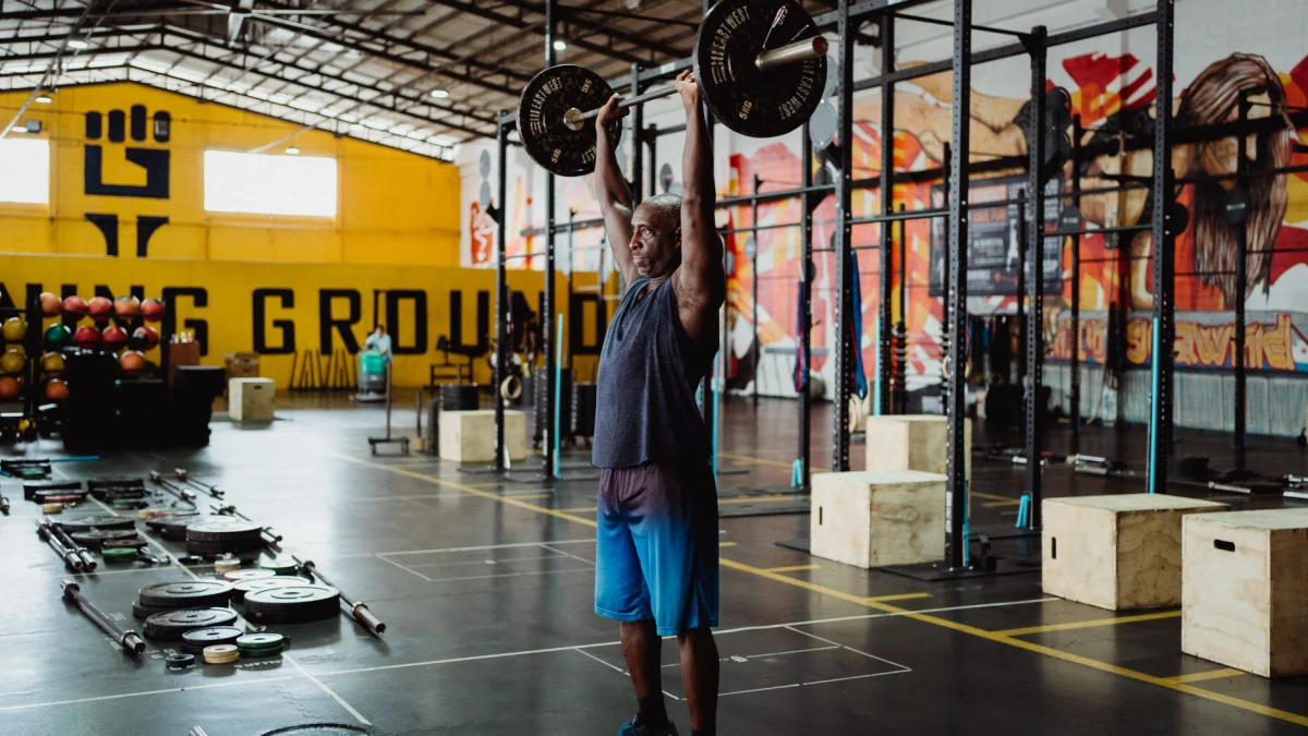 Volwassen man voert gewichthefoefening uit in een industriële sportschool en toont kracht en fitness.
