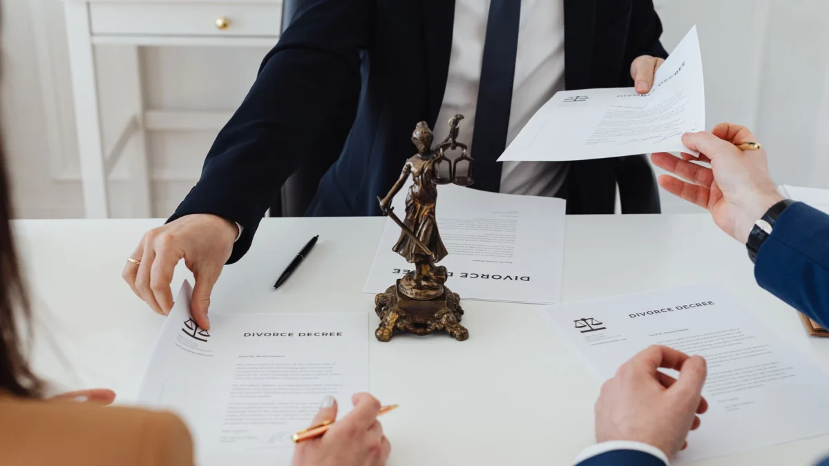 Drie volwassenen bespreken echtscheidingsdocumenten in een formele kantooromgeving met een juridische standbeeld in beeld.