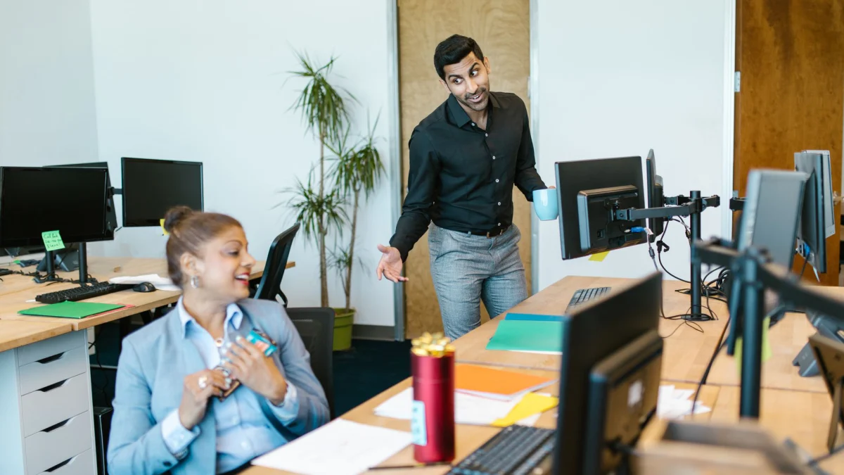 Twee collega's zijn in een modern kantoorgebouw in een vrolijk gesprek verwikkeld.