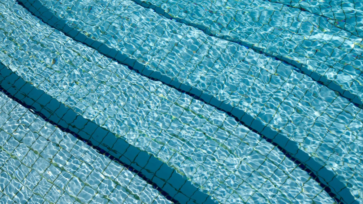 Een gedetailleerd uitzicht op het kristalheldere zwembadwater boven een betegelde vloer, dat de rustige en verfrissende aard toont.