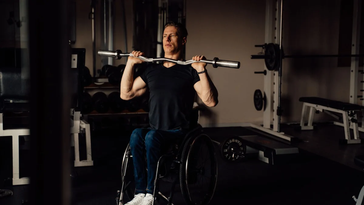 Een vastberaden man in een rolstoel die gewichten heft in een sportschool, toont kracht en fitness.