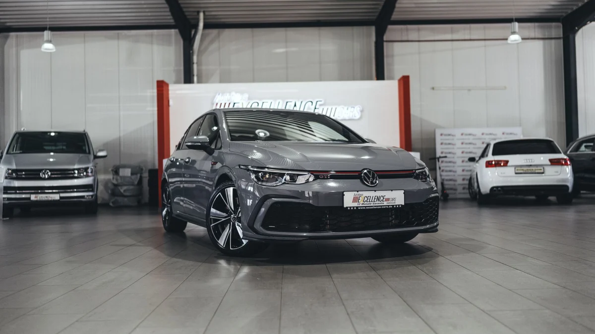 Een slanke Volkswagen auto in een moderne binnenshowroom met verschillende voertuigen.