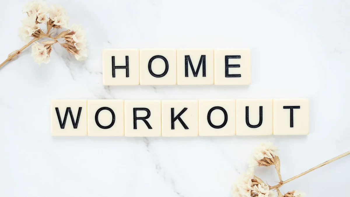 Stijlvolle lettertegels die 'Thuis Workout' spellen op een schone marmeren achtergrond met bloemaccenten.